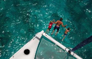 Two children and a man jumping from a boat
