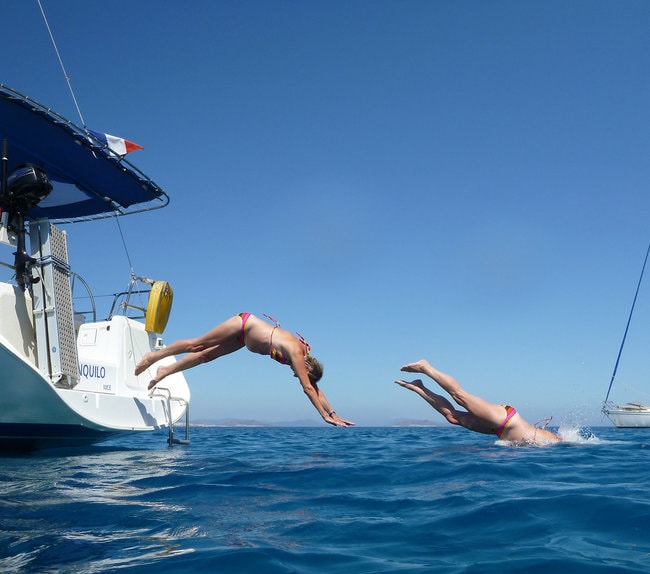 Friends jumping in the water from a boat